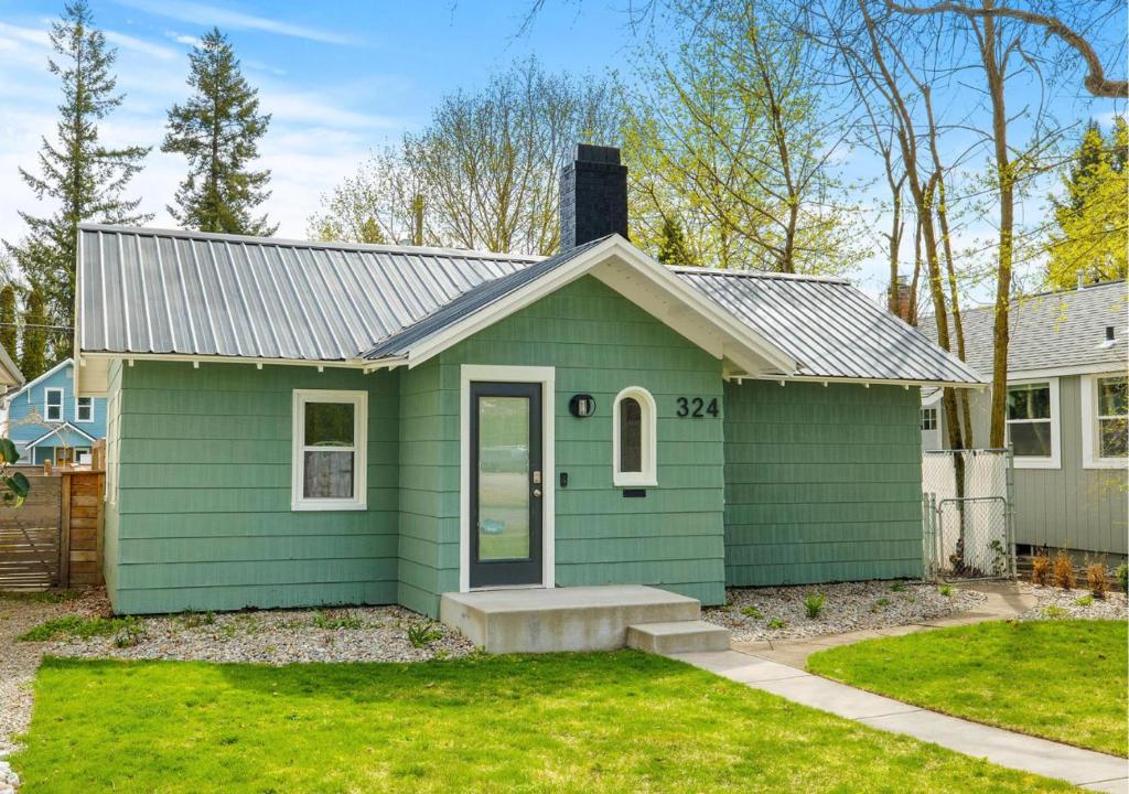 a green house with a grass yard in der Unterkunft Gorgeous Downtown Bungalow in Coeur d'Alene