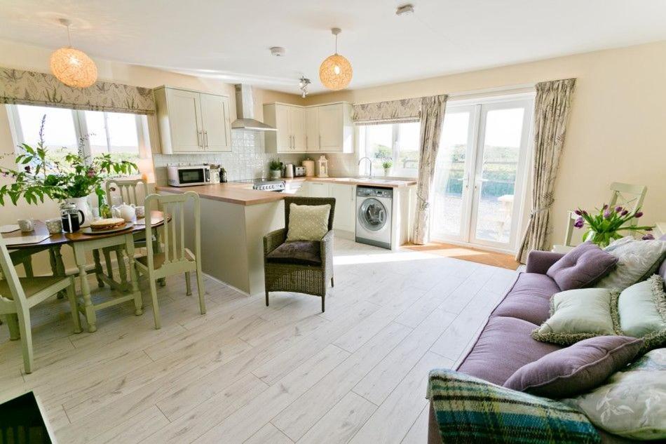 a large living room with a couch and a kitchen at Hideaway in Rhosneigr