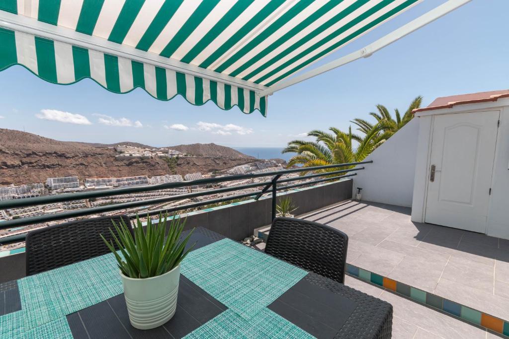 a balcony with a table and chairs and a view of the ocean at Hilltop Vista Apartment in Puerto Rico de Gran Canaria