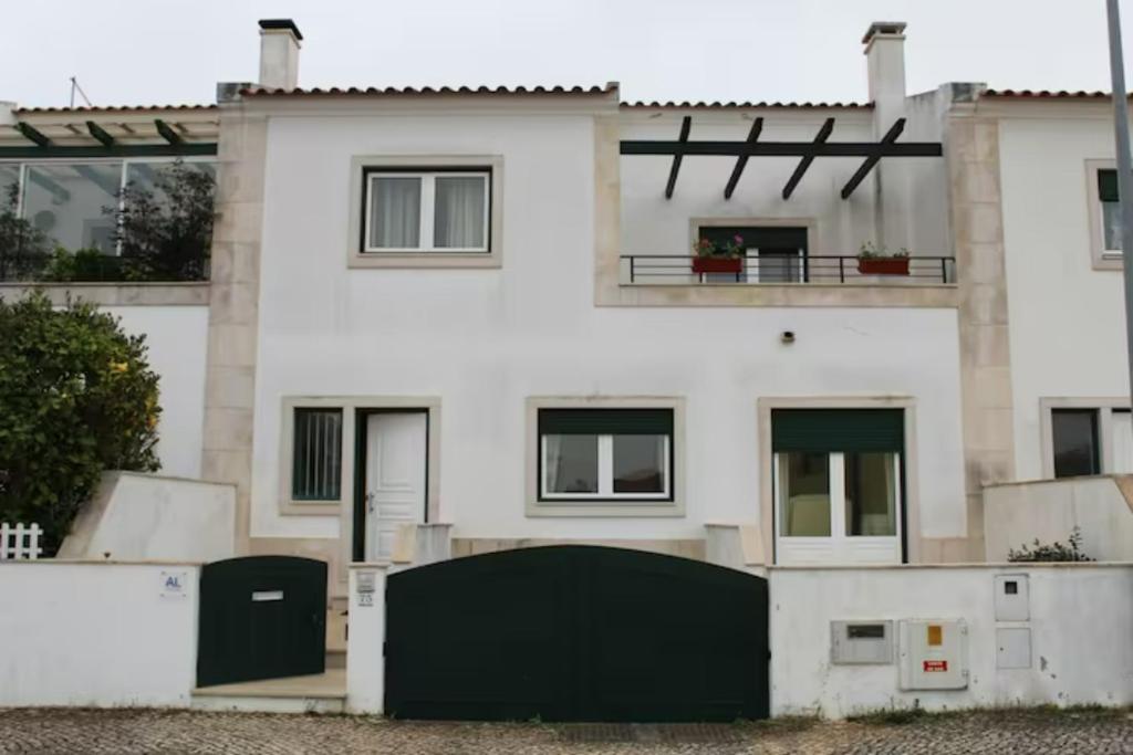 une maison blanche avec une clôture noire devant elle dans l'établissement Casa dos Limões, à Caldas da Rainha