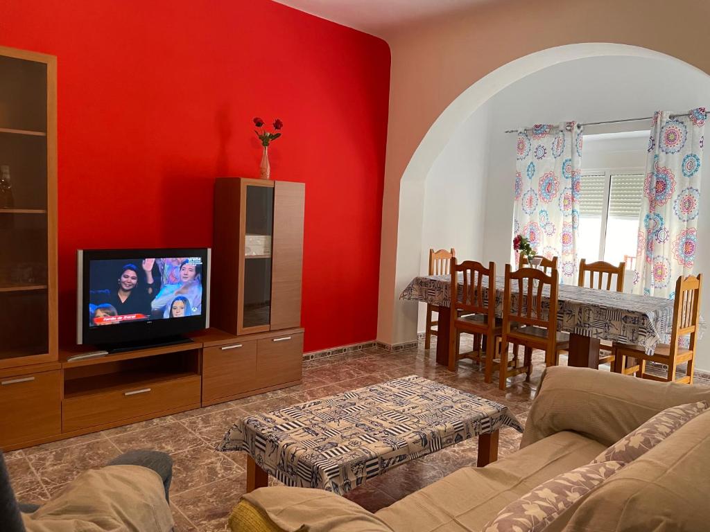 a living room with a tv and a dining room at Casa sebas in Puerto de Mazarrón