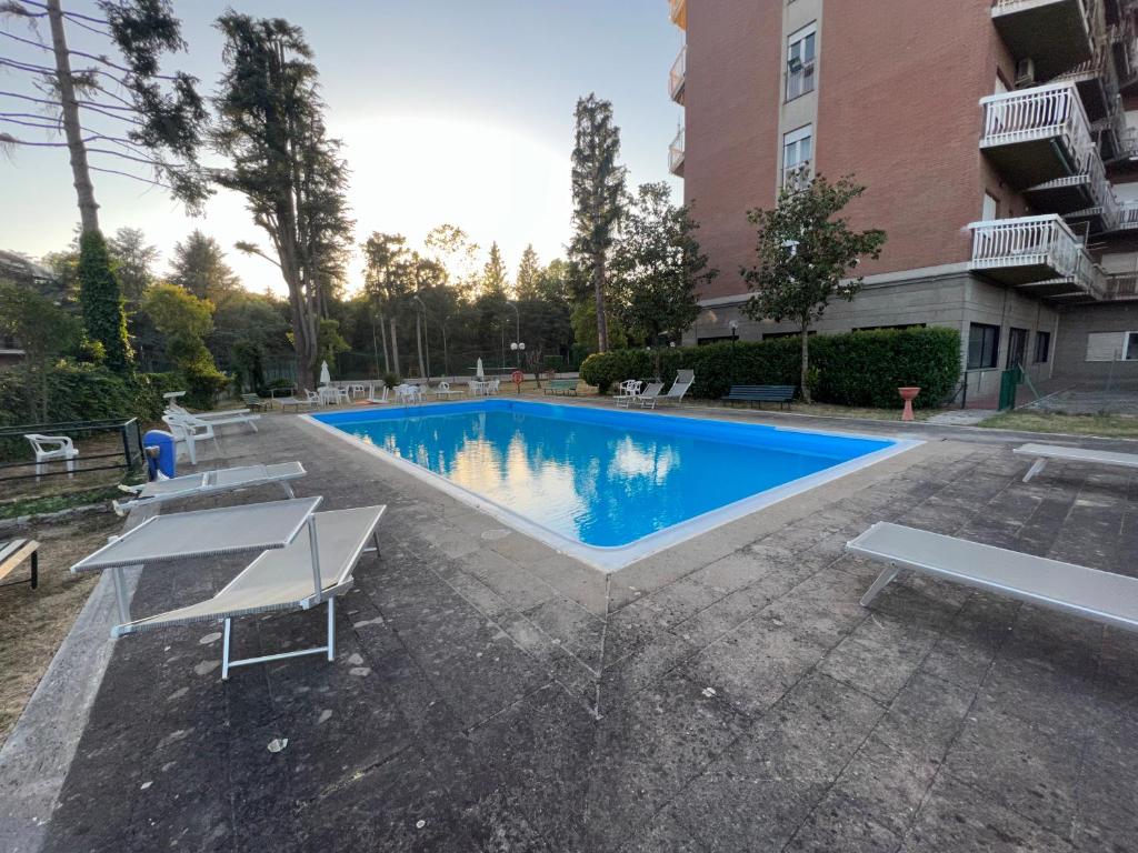 a swimming pool with benches and a building at Appartamento monolocale Fiuggi 14 MQ piscina dal 20 giugno al 15 settembre in Fiuggi
