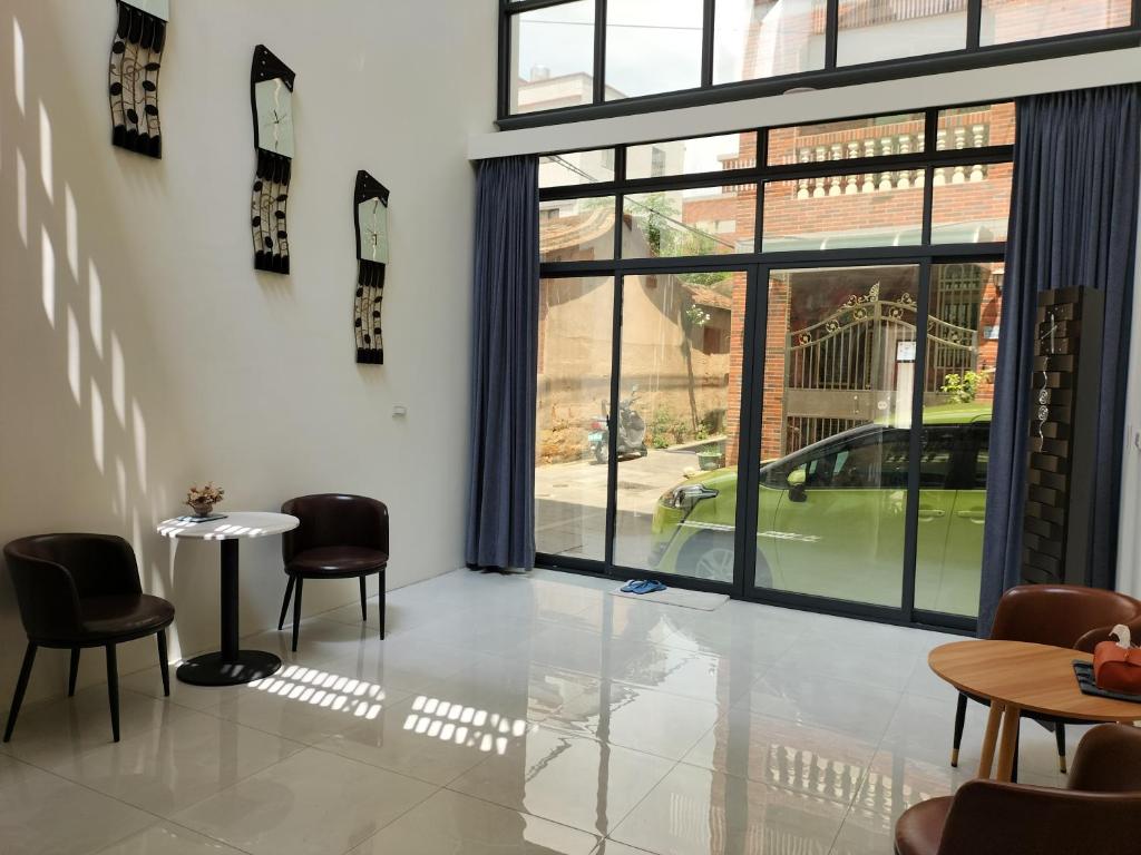 a room with chairs and a table and a large window at Jing Cheng Homestay in Jincheng