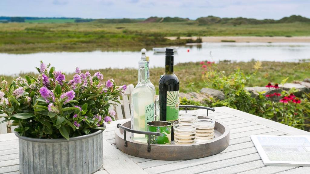 una botella de vino sentada en una mesa con flores en Min y Don en Aberffraw