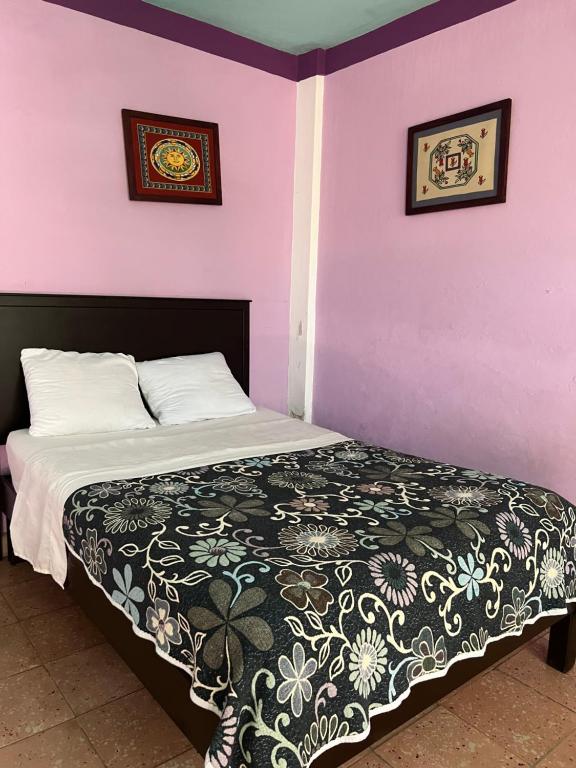 a bedroom with a bed with purple walls at Villas Velarde in Cozumel