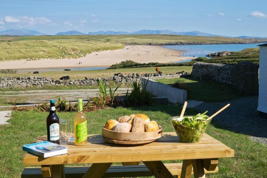 a picnic table with a basket of bread and a bottle of wine at Penrhyn Gwyn in Aberffraw