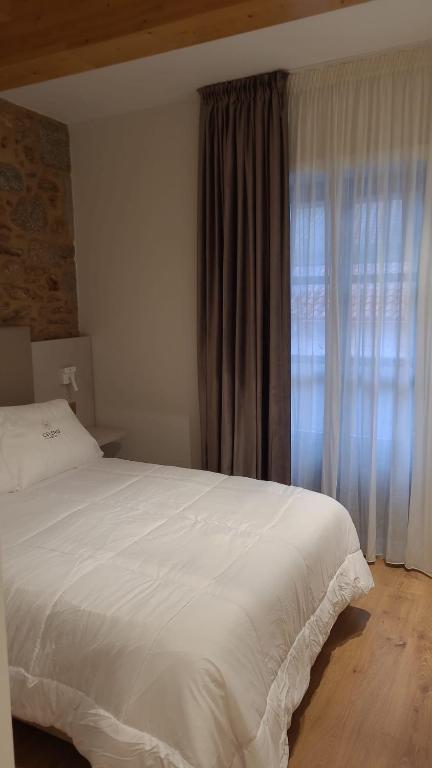 Un dormitorio con una gran cama blanca y una ventana en hostal Hcelenis, en Caldas de Reis