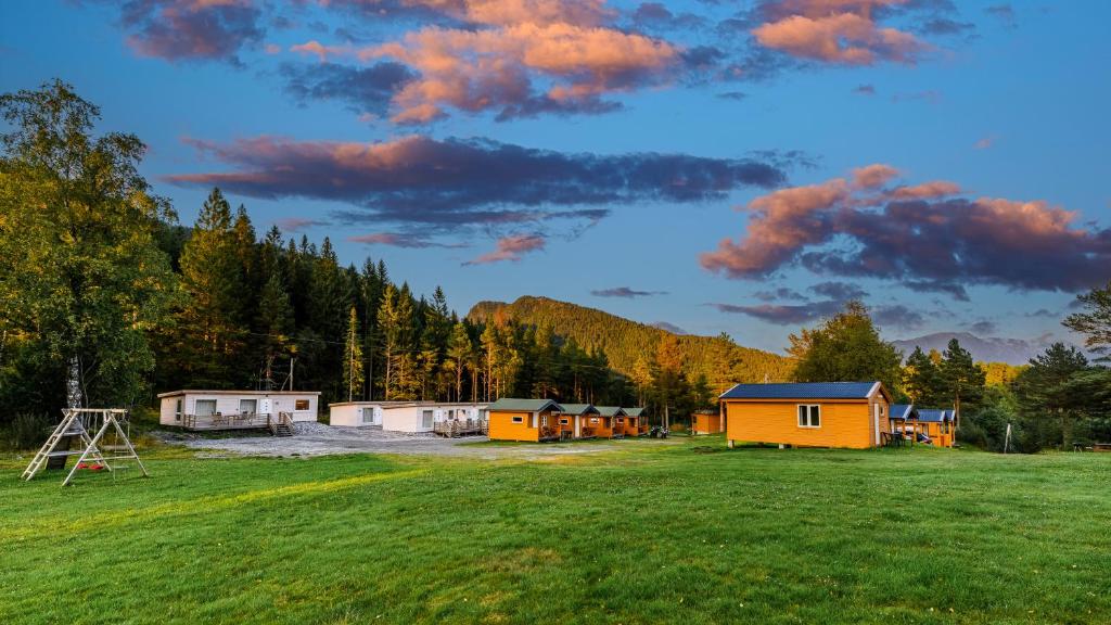a group of buildings in a field with trees at Korsbakken Camping in Isfjorden