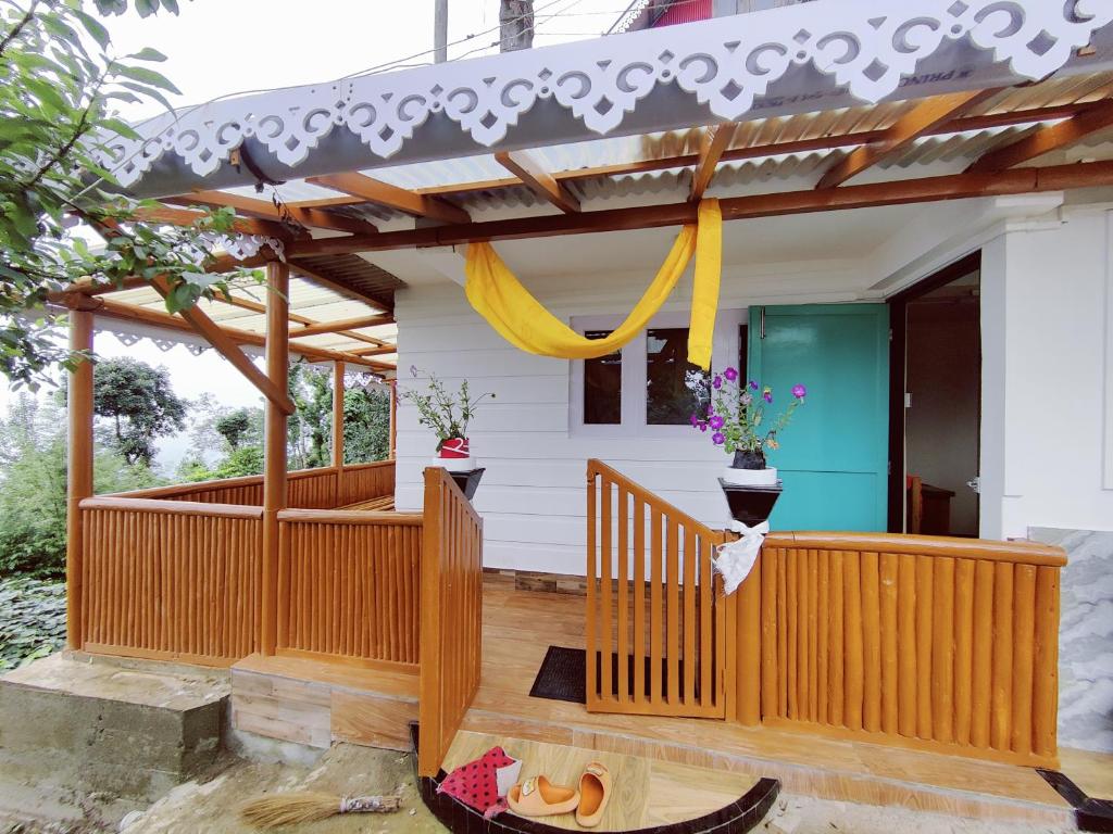 a house with a wooden porch with a yellow ribbon at Mandala Fram Stay in Darjeeling