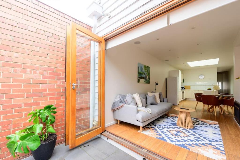 uma sala de estar com uma parede de tijolos e um sofá em Eden-Stay like locals in Fitzroy North em Melbourne