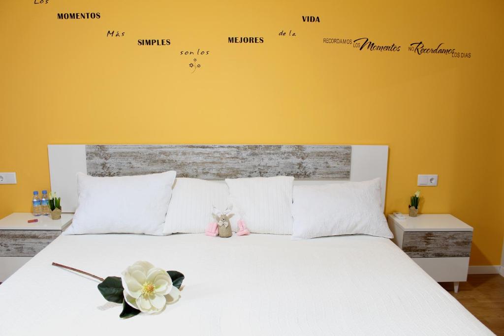 a bedroom with a white bed with a yellow wall at Hostal Imperial Merida in Mérida