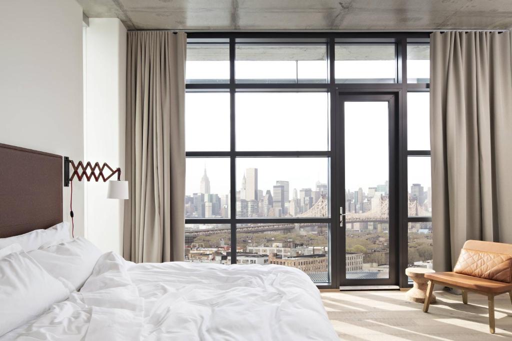 ein Schlafzimmer mit einem weißen Bett und einem großen Fenster in der Unterkunft Boro Hotel in Queens