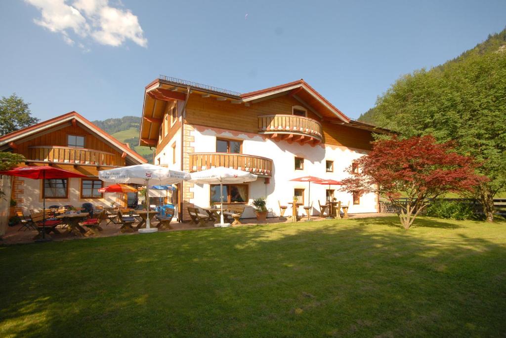 a house with tables and umbrellas in a yard at Frühstücks- & Apartmenthaus Maislau in Rauris