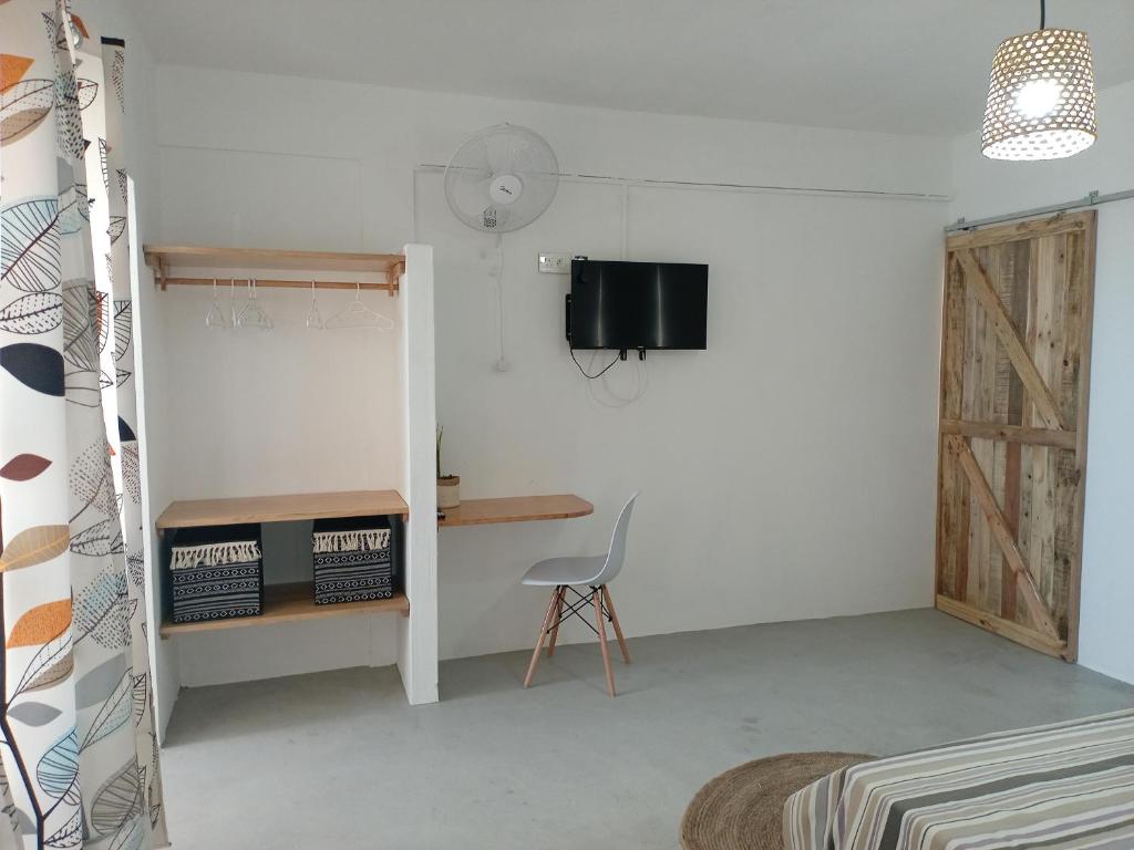 IZAVA LODGE في Rodrigues Island: غرفة بها كرسي ومكتب وتلفزيون