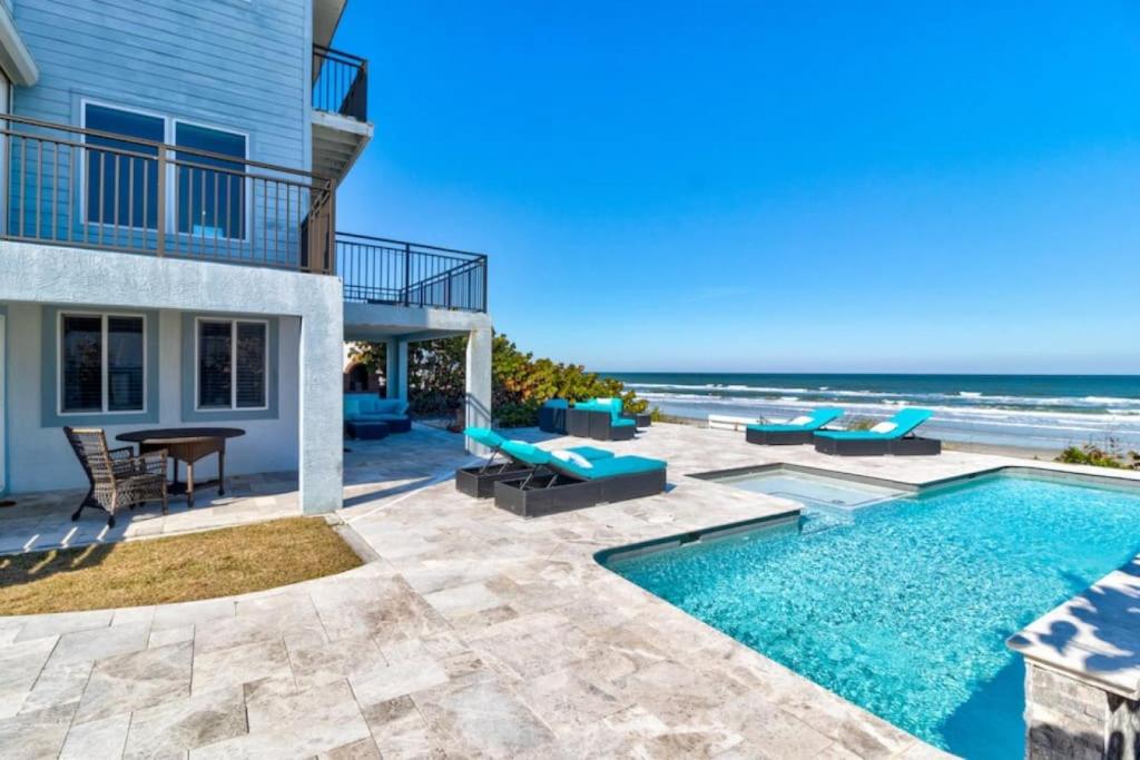 a house with a swimming pool next to the beach at Oceanfront Pool House 7 Bedrooms 7 Bath 2 Kitchens in Port Orange