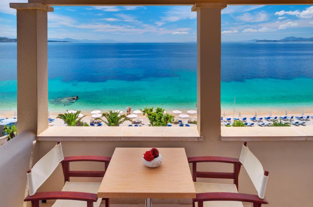 een tafel en stoelen in een kamer met uitzicht op het strand bij Krouzeri Beach Apartments in Nisakion