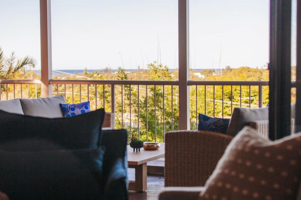 een woonkamer met stoelen en een tafel en een balkon bij Cheerful family home with stunning views in Caloundra