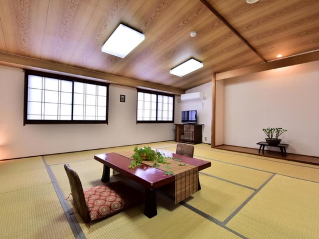 Habitación grande con mesa, sillas y ventanas. en Ｇｕｅｓｔ Ｈｏｕｓｅ Ｔａｋｅｎｏｙａ - Vacation STAY 76200v en Omachi