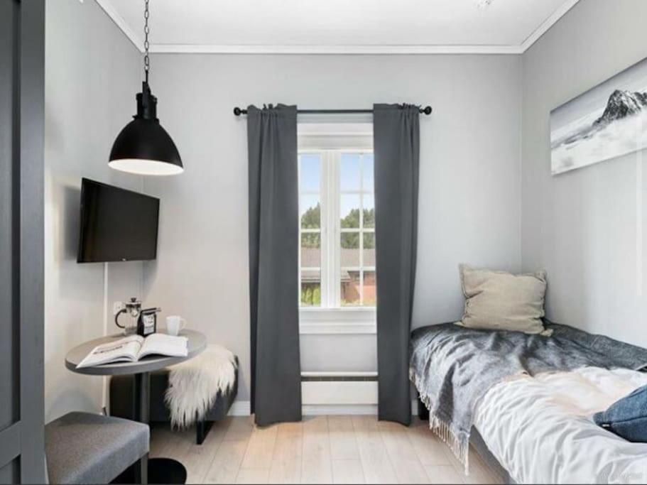 a bedroom with a bed and a table and a window at Comfy studio apt by Oslo Airport in Garder