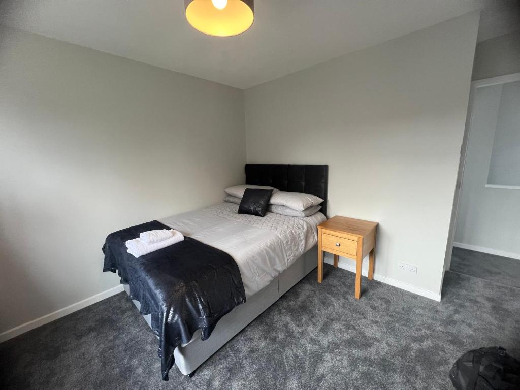 a bedroom with a bed and a wooden table at The Coral Guest House 1 Fratton Park Portsmouth in Portsmouth