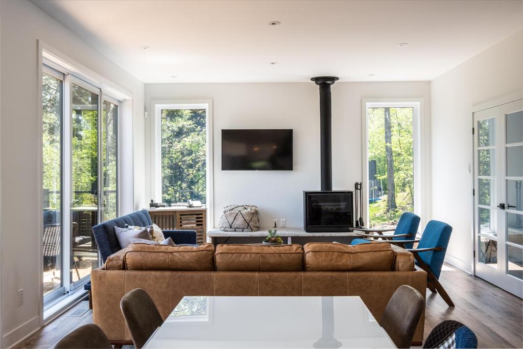 a living room with a brown couch and chairs at Chalet Alpine by Tremblant Platinum in La Conception