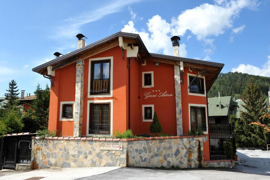 una casa roja con una valla delante en Garnì Astoria Hotel & SPA, en Roccaraso