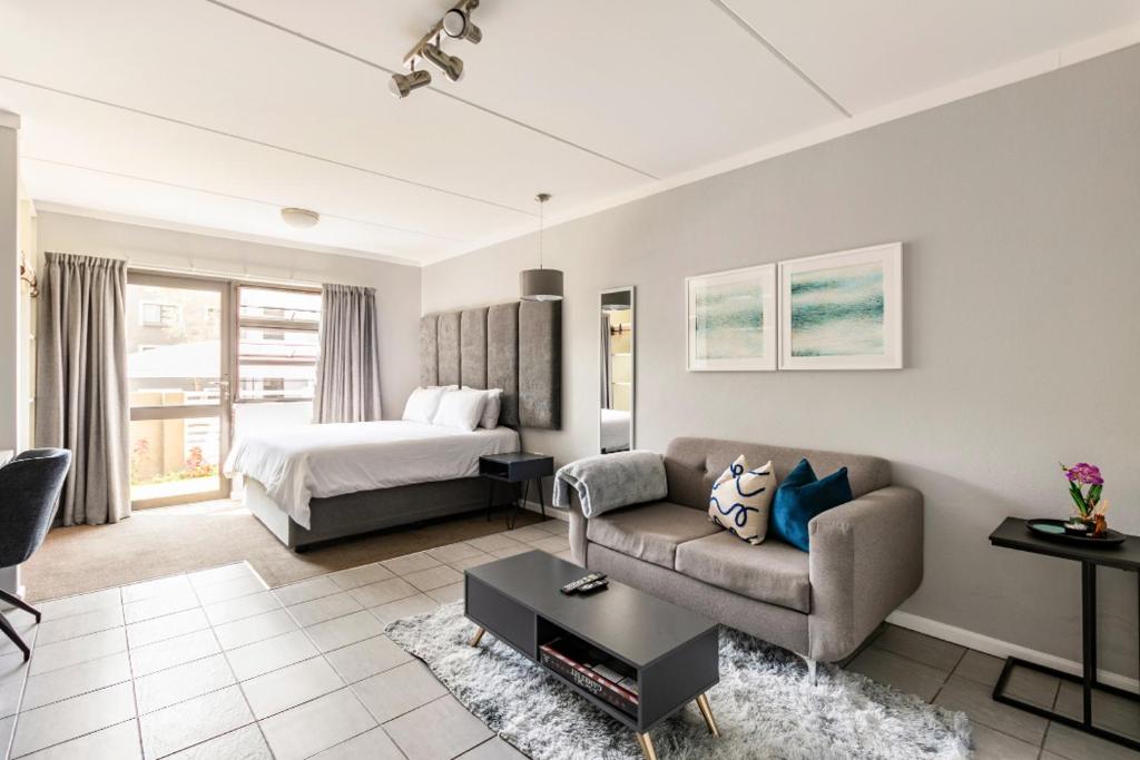 a living room with a couch and a bed at Lea's Furnished Apartments - Dainfern in Sandton