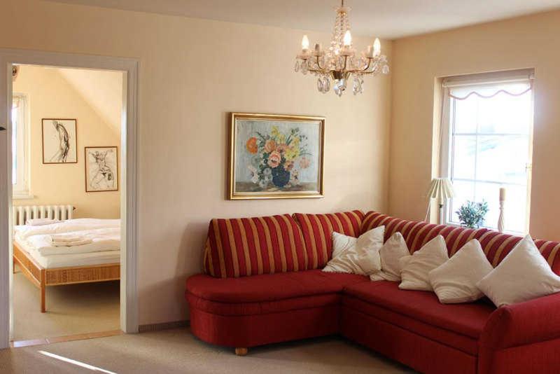 ein Wohnzimmer mit einem roten Sofa und einem Bett in der Unterkunft Ferienwohnung Rundumblick in Sassnitz