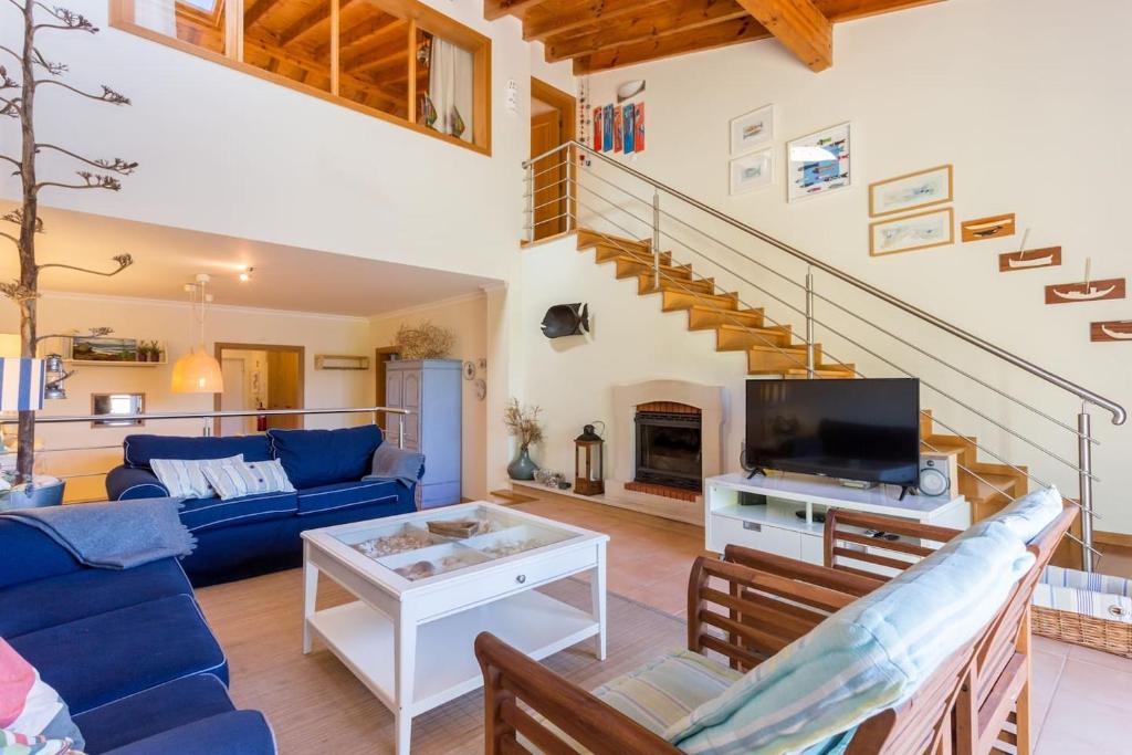 Pita's House - Villa Sagres 2 في ساغريس: غرفة معيشة مع أريكة زرقاء وتلفزيون