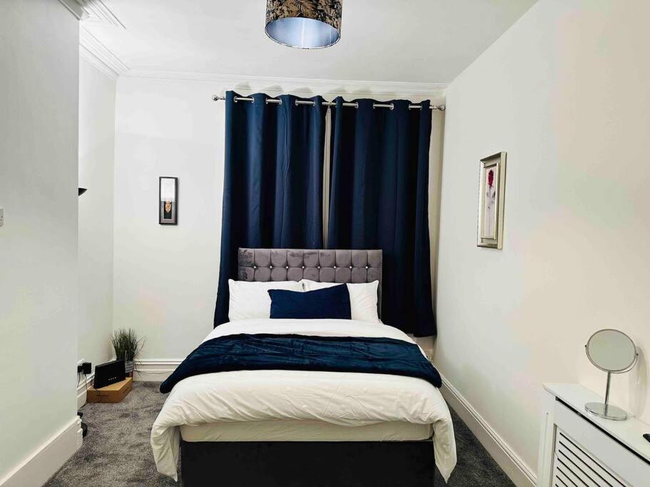 a bedroom with a bed with a blue curtain at Bespoke 2 Bedroom Apt Derby City in Derby
