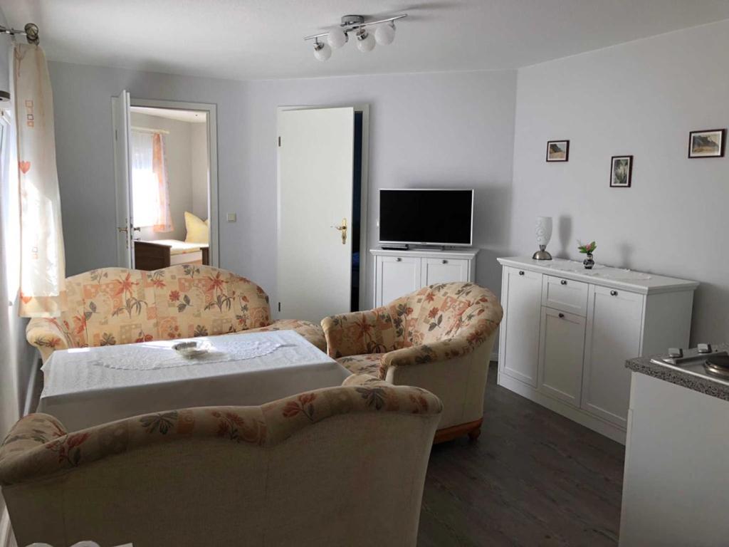 ein Wohnzimmer mit 2 Stühlen, einem Bett und einem TV in der Unterkunft Ferienhaus Karger in Marlow