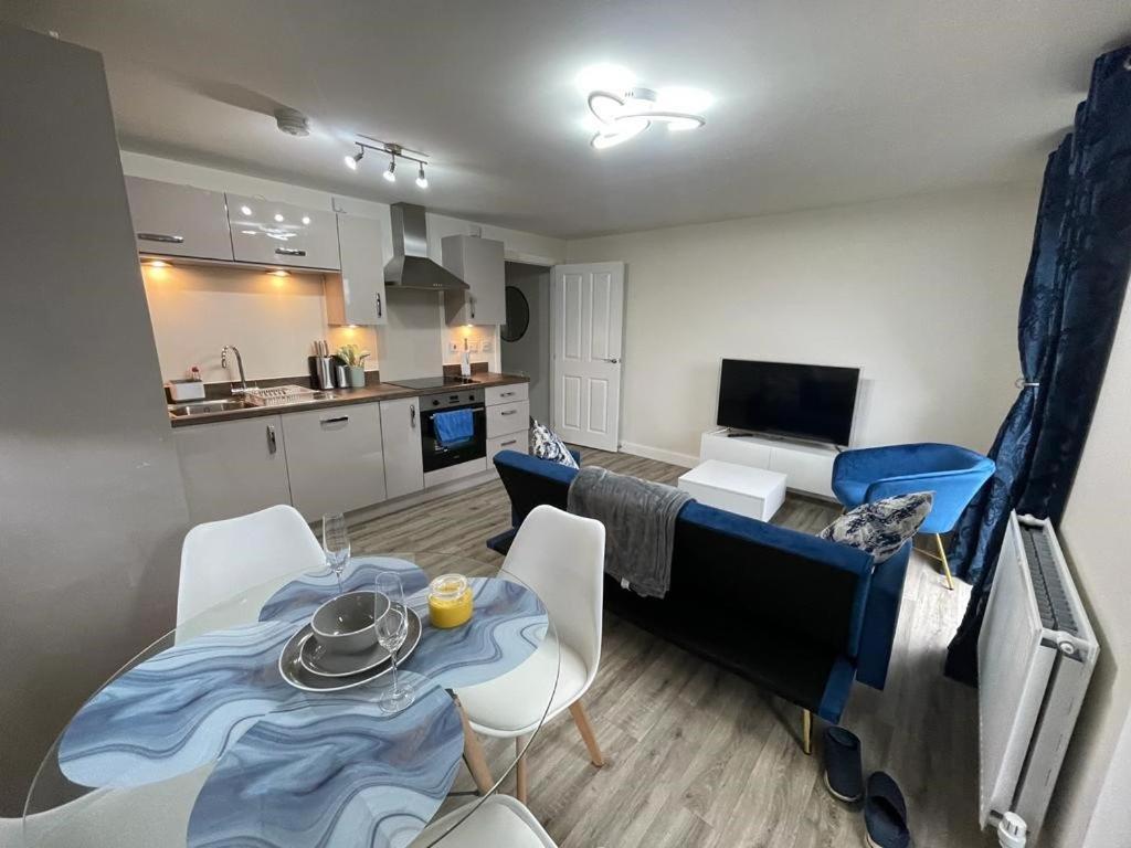 Luxurious Apartment in Brooklands في ميلتون كينز: مطبخ وغرفة معيشة مع طاولة وكراسي