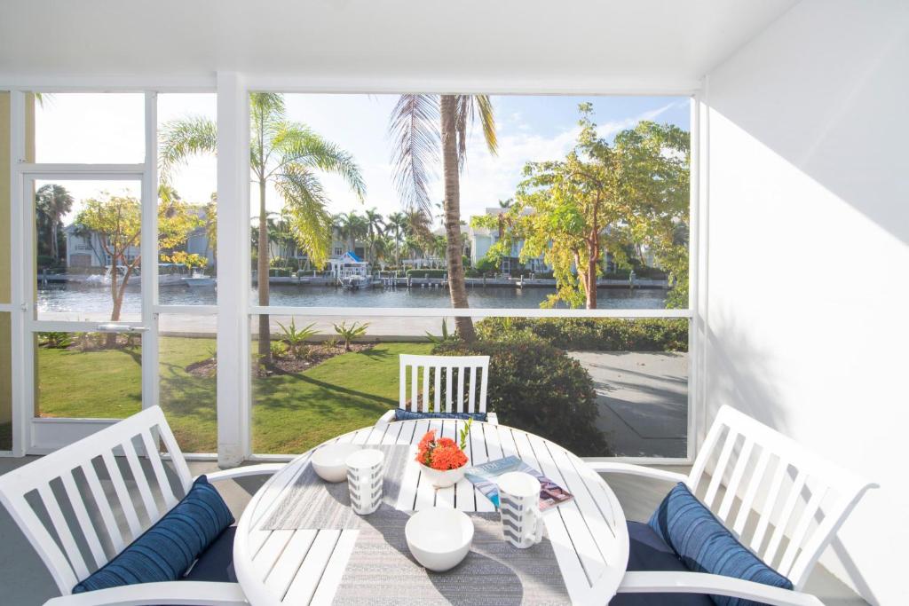 einen Tisch und Stühle auf einer Veranda mit Blick auf das Wasser in der Unterkunft Snug Harbour View Condo #3 in George Town