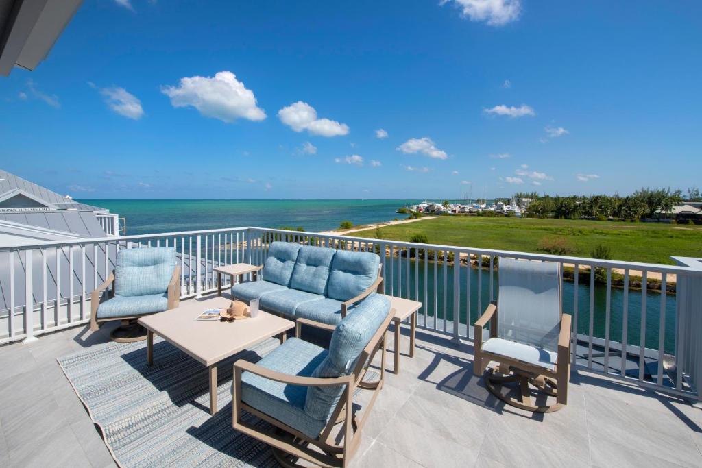 a balcony with chairs and a table and the ocean at Mahogany Villa 2-A / 4BR 