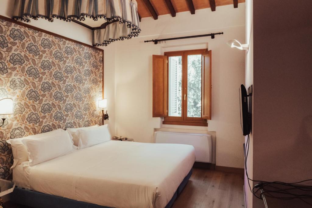 ein Schlafzimmer mit einem weißen Bett und einem Fenster in der Unterkunft II Guelfo Bianco in Florenz