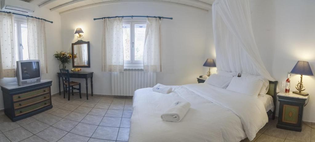 a bedroom with a white bed and a tv at Zephyros in Paraga