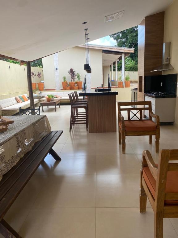 a living room with tables and chairs and a kitchen at Casa Canto do Bambu in Delfinópolis