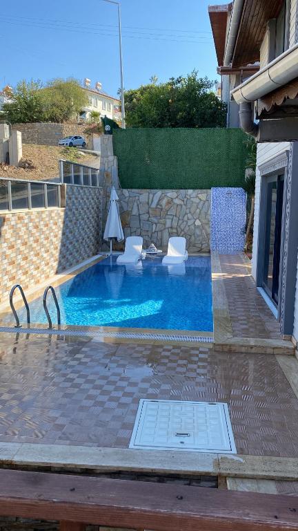 uma pequena piscina com duas cadeiras e uma mesa em Luxus Villa Kargicak em Kargicak