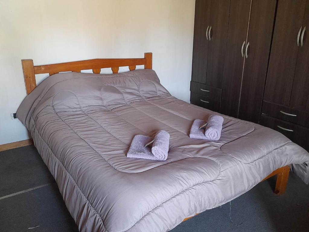 1 cama con 2 zapatillas y 2 almohadas en Alquileres patagonicos en San Carlos de Bariloche