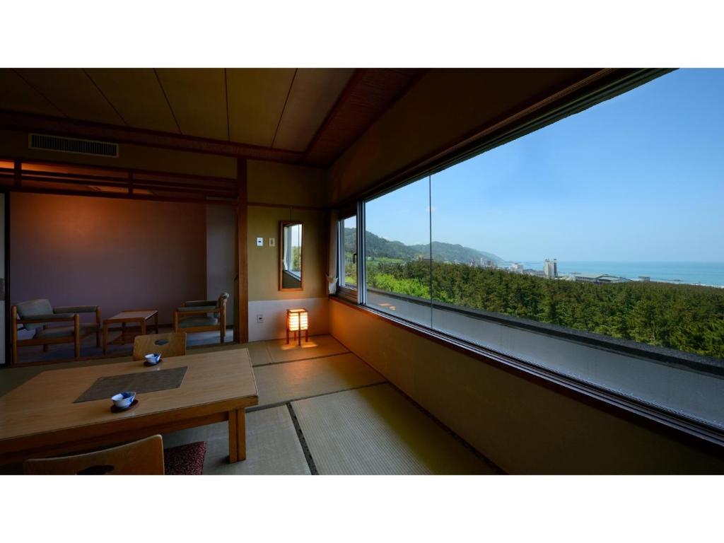 um quarto com uma mesa e uma grande janela em Yunohama Onsen Hanayubi Nihonkai - Vacation STAY 67572v em Tsuruoka