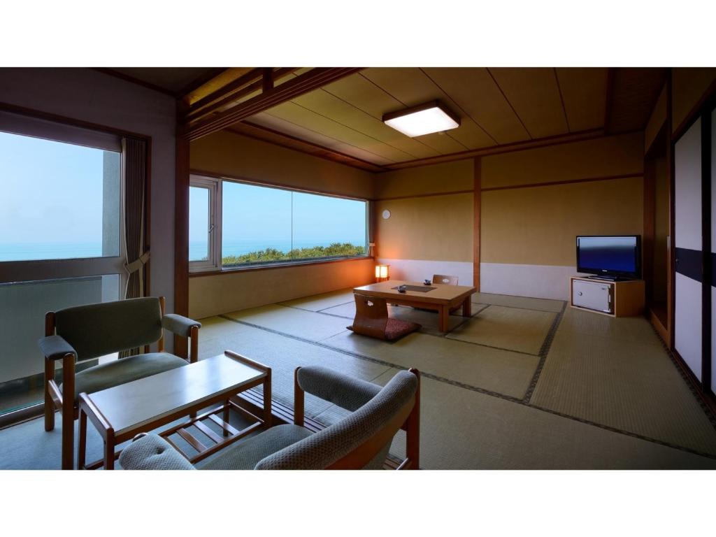 a living room with a table and chairs and a tv at Yunohama Onsen Hanayubi Nihonkai - Vacation STAY 67567v in Tsuruoka