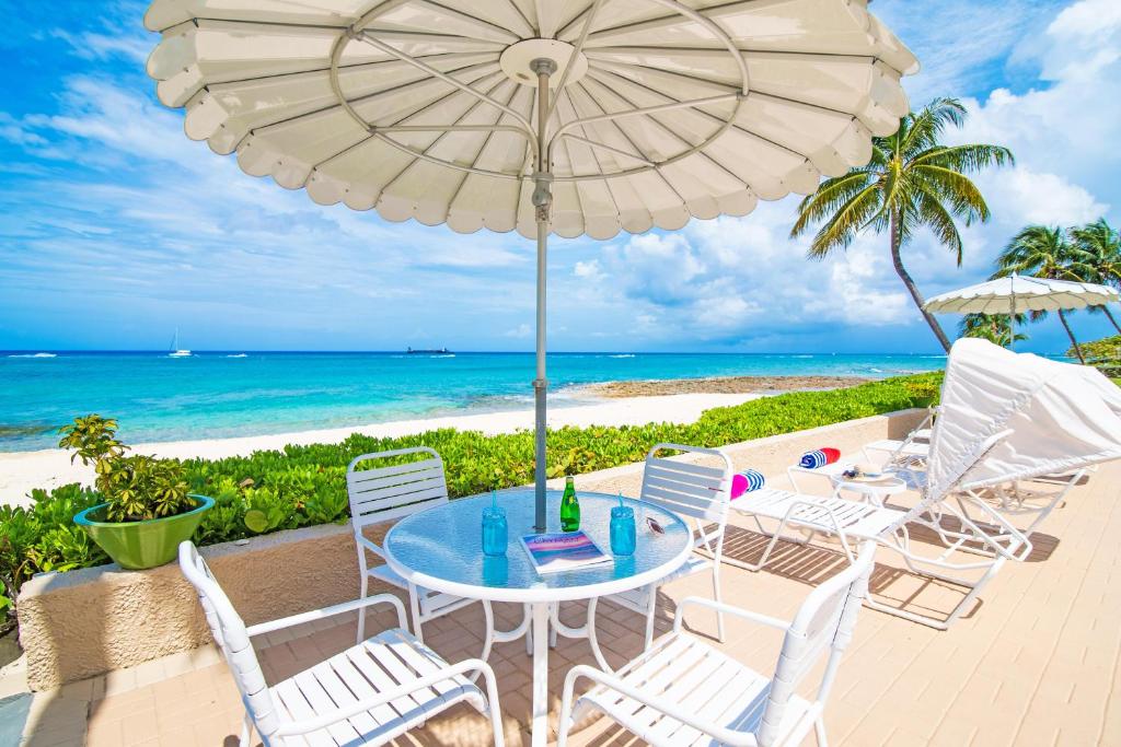 a table and chairs on the beach with an umbrella at Cocoplum #5 Condo in George Town