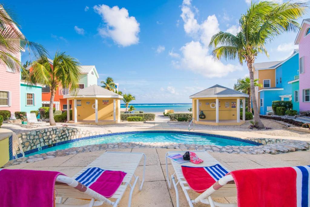 a swimming pool with two lounge chairs and the ocean at Cayman Paradise Villa #1 in Sand Bluff
