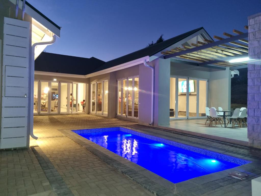 a swimming pool in front of a house at night at Villa 206 Clarens Golf Estate in Clarens