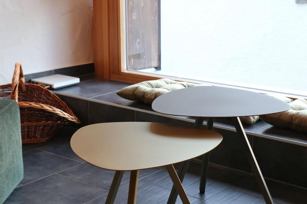 zwei Tische und Stühle neben einem Fenster in der Unterkunft Appartement de vacances in Saulcy