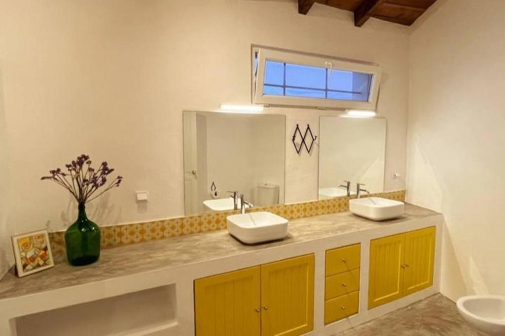 uma casa de banho com 2 lavatórios e um espelho grande em Casa das Chaminés em Santo António do Baldio