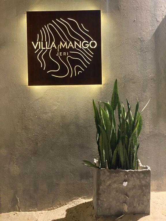 a plant in a pot next to a sign on a wall at Villa Mango Jeri in Jericoacoara