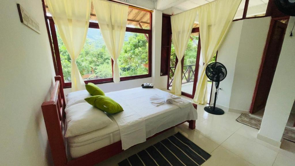 a bedroom with a bed and a large window at Hotel talú tayrona in El Zaino