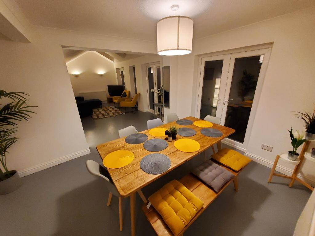 a dining room with a wooden table and yellow chairs at 5 bedroom, recently renovated house close to Hastings Beach in Hastings