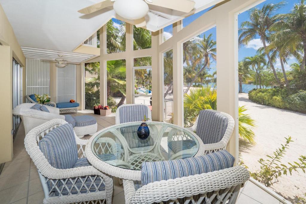 a conservatory with a glass table and chairs on a patio at Island House #12 at Rum Point in Driftwood Village
